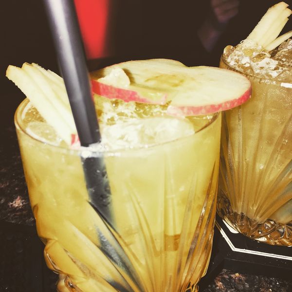 Zwei goldene Drinks mit Apfelscheiben in Kristallgläsern