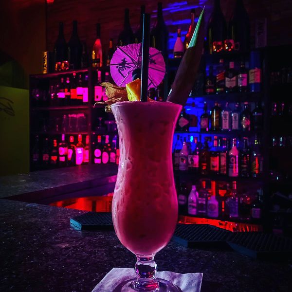 Pinker Cocktail vor der beleuchteten Backbar