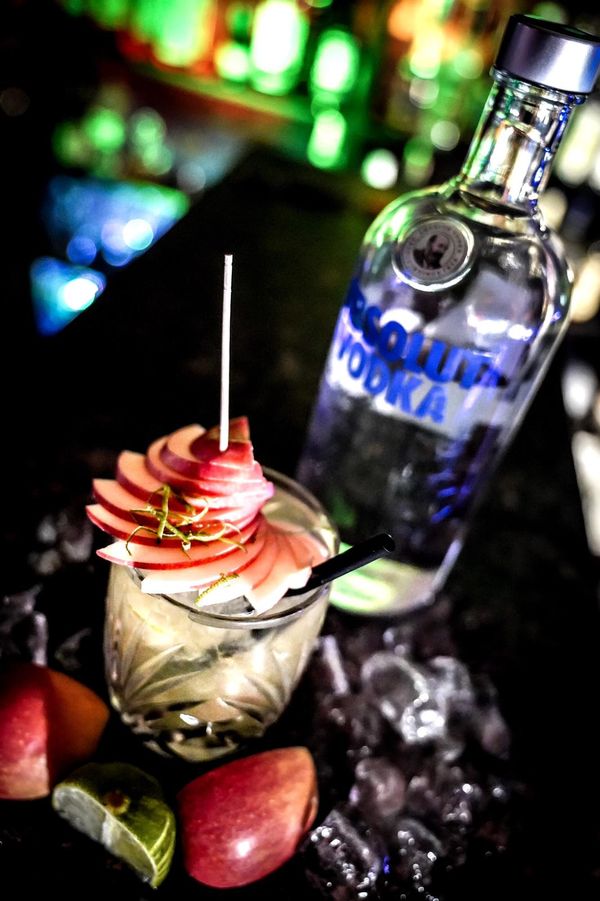 Cocktail mit Apfelfächer und Vodka-Flasche