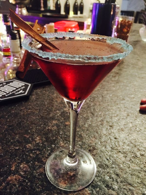 Roter Cocktail im Martiniglas mit Zuckerrand und Zimtstange